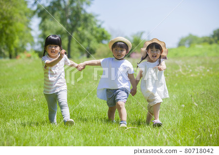 Three girls playing in a lawn park 80718042