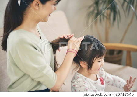 Girl having her mom tie her hair 80718549