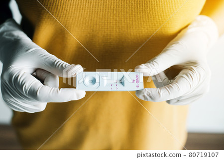 Patient woman showing result a covid-19 self test rapid antigen testing kit at home Patient woman showing result a covid-19 self test rapid antigen testing kit at home 80719107