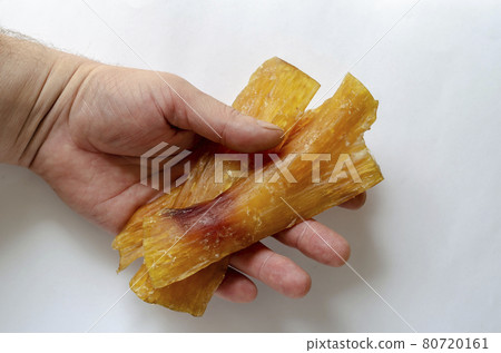 Dried beef tendon in the hand. 80720161