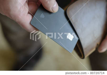 Hand takes out a bank card from the wallet. Adult man holds a black bank card. Payment for goods in the store. Selective focus. Close-up. Hand takes out a bank card from the wallet. Adult man holds a black bank card. Payment for goods in the store. Selective focus. Close-up. 80720714