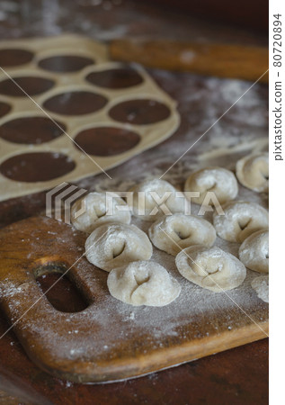Homemade food. Raw dumplings with meat on a wooden cutting board. 80720894