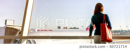 Airpot travel panoramic background of woman tourist looking at window airplanes on tarmac with carry-on luggage bag banner. First class business trip lounge waiting to board flight at gate departure 80721714