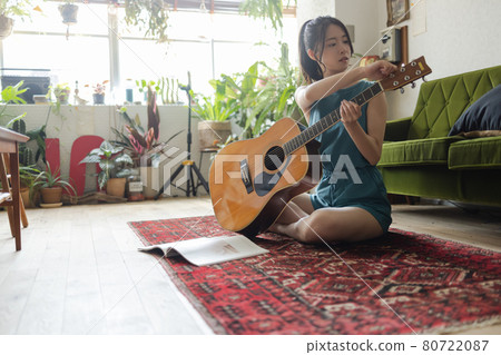 Young woman practicing guitar in the room 80722087