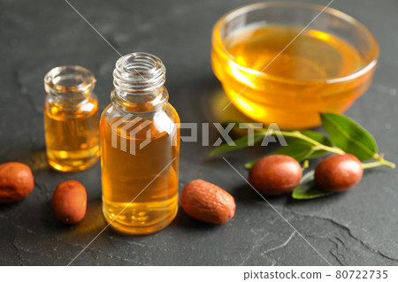 Jojoba oil and seeds on dark grey table Jojoba oil and seeds on dark grey table 80722735