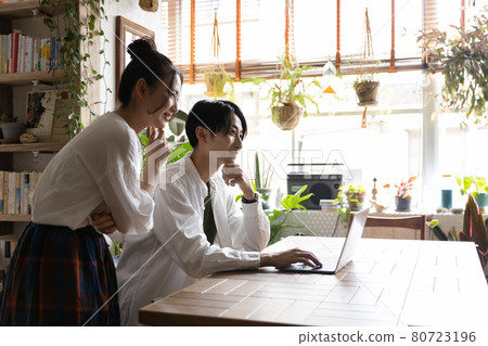 Young men and women looking at a computer in the room Young men and women looking at a computer in the room 80723196