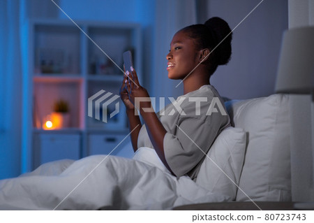 woman with smartphone in bed at home at night woman with smartphone in bed at home at night 80723743