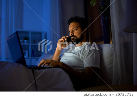 indian man with laptop calling on phone at night indian man with laptop calling on phone at night 80723752