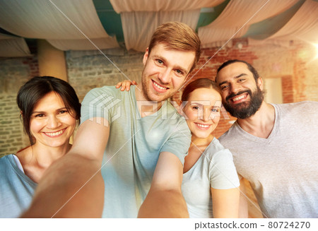 happy friends at yoga studio or gym taking selfie 80724270