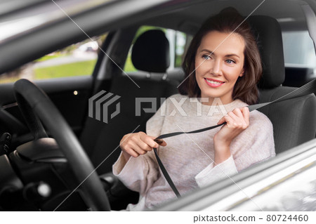 woman or female car driver fastening seat belt 80724460