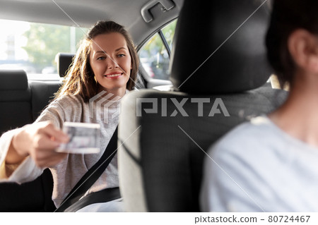 female passenger giving money to taxi car driver 80724467