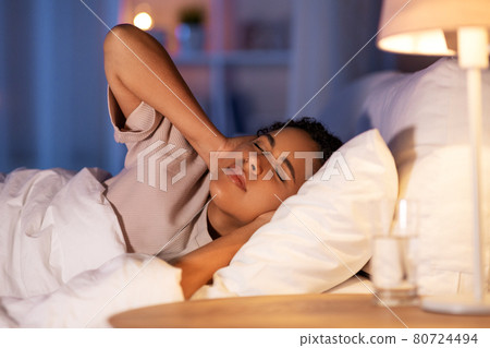 angry african woman lying in bed and closing ears 80724494
