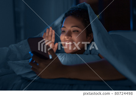 woman with phone having video call in bed at night woman with phone having video call in bed at night 80724498