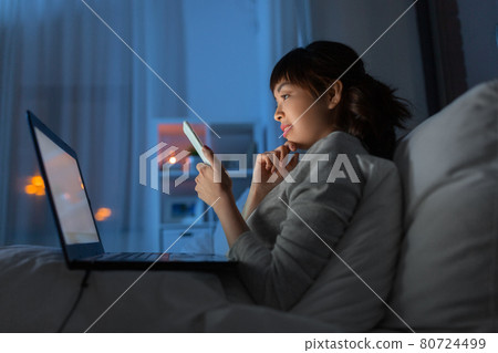 asian woman with smartphone in bed at night asian woman with smartphone in bed at night 80724499