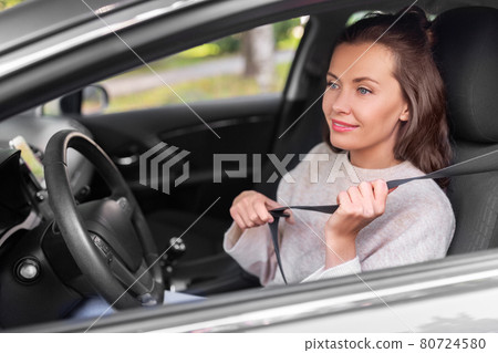 woman or female car driver fastening seat belt woman or female car driver fastening seat belt 80724580