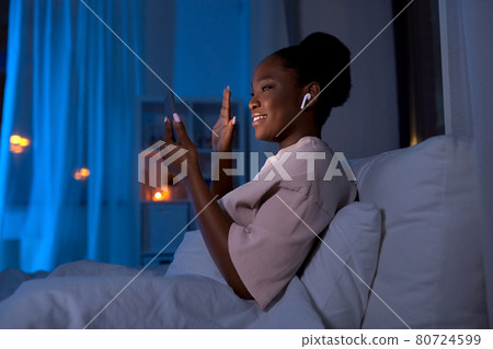 woman with phone having video call in bed at night woman with phone having video call in bed at night 80724599