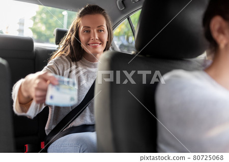 female passenger giving money to taxi car driver 80725068