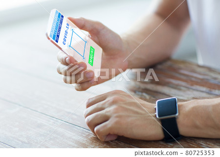 hand with certificate of vaccination on smartphone 80725353