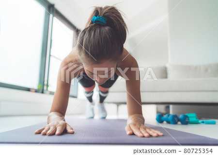 Plank exercise at home. Woman doing online fitness class body core workout on yoga mat 80725354