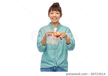 happy woman putting apple into reusable bag 80725614