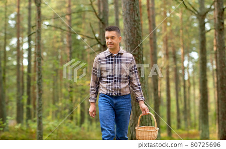 happy man with basket picking mushrooms in forest 80725696