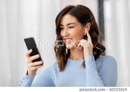 woman with earphones and smartphone at home 80725824