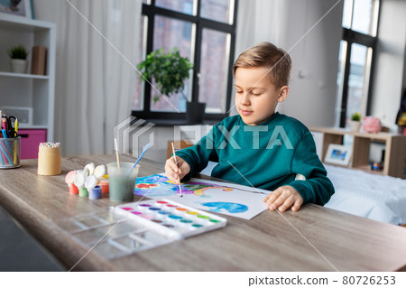 boy with colors and brush drawing picture at home 80726253