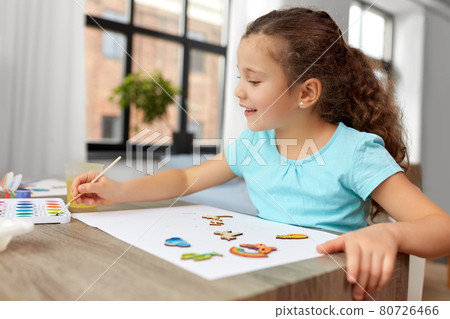 little girl painting wooden items at home 80726466