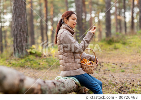 woman with mushrooms in basket in autumn forest 80726468