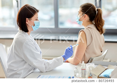 female doctor with syringe vaccinating patient female doctor with syringe vaccinating patient 80726493