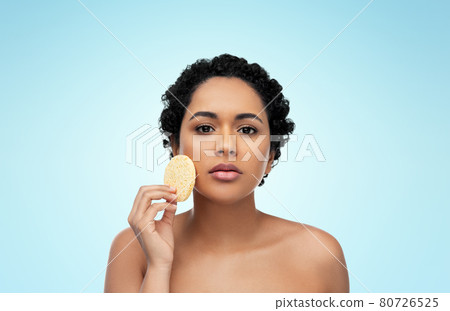 young woman cleaning face with exfoliating sponge young woman cleaning face with exfoliating sponge 80726525