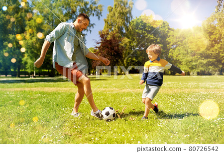 father with little son playing soccer at park 80726542