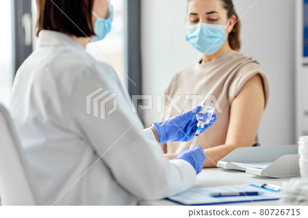 female doctor with syringe vaccinating patient 80726715