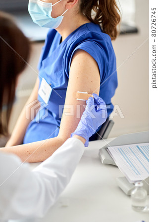doctor attaching patch to medical worker 80726745