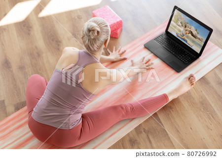 woman with laptop having online yoga class woman with laptop having online yoga class 80726992