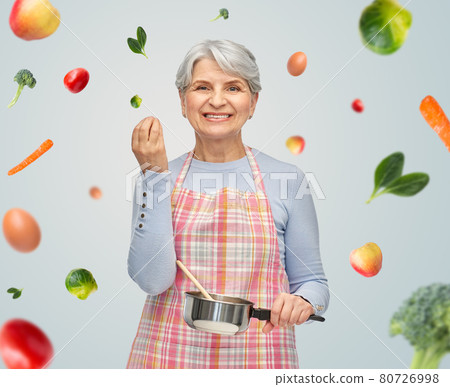 senior woman in apron with pot cooking food senior woman in apron with pot cooking food 80726998