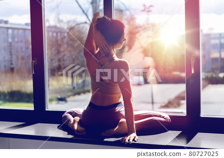 woman doing yoga exercise on window sill at studio woman doing yoga exercise on window sill at studio 80727025