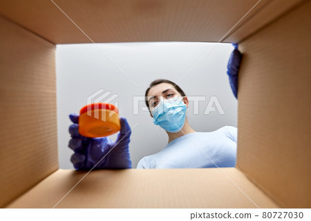 woman in mask unpacking parcel box with cosmetics woman in mask unpacking parcel box with cosmetics 80727030