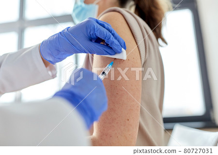 female doctor with syringe vaccinating patient female doctor with syringe vaccinating patient 80727031