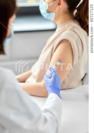 female doctor with syringe vaccinating patient 80727120