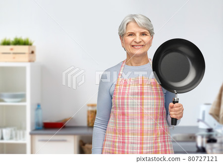 smiling senior woman with frying pan at kitchen 80727121