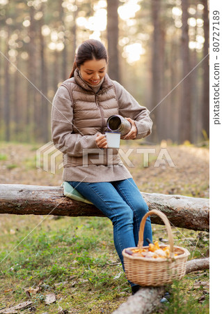 asian woman with thermos drinking tea in forest asian woman with thermos drinking tea in forest 80727189