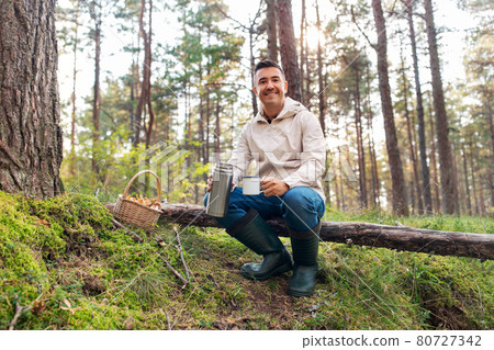 man with basket of mushrooms drinks tea in forest man with basket of mushrooms drinks tea in forest 80727342