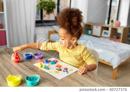 little girl with modeling clay playing at home 80727378