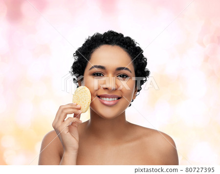 young woman cleaning face with exfoliating sponge 80727395