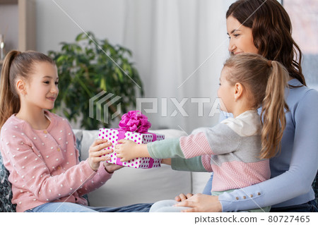 girl giving present to younger sister at home 80727465