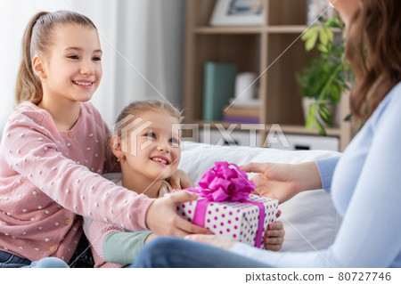 daughters giving present to happy mother 80727746