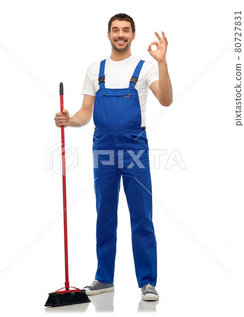 male cleaner in overall cleaning floor with broom 80727831