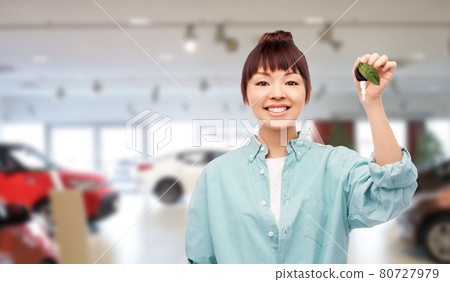 happy asian woman holding car key with green leaf happy asian woman holding car key with green leaf 80727979