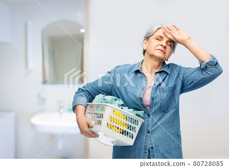 tired senior woman with laundry basket tired senior woman with laundry basket 80728085